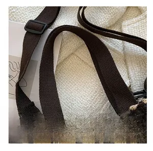 Close-up of brown houndstooth canvas bag with adjustable strap and sturdy handles