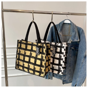 Detail of canvas tote bags with artistic grid patterns and cute bear charms