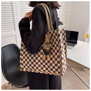 Checkerboard canvas tote bag shown on shoulder with cute rabbit plush keychain detail