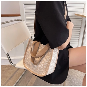 Floral canvas crossbody bag with brown straps shown on shoulder in minimalist room