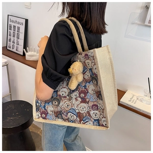 Detail of a large linen tote bag with teddy bear jacquard and a plush bear pendant