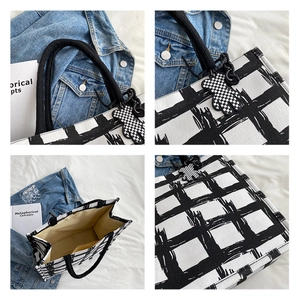 Detail view of large checkered canvas tote bag with woven handles and bear charm