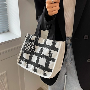 Minimalist checkered canvas tote bag with bear charm shown in a chic lifestyle setting