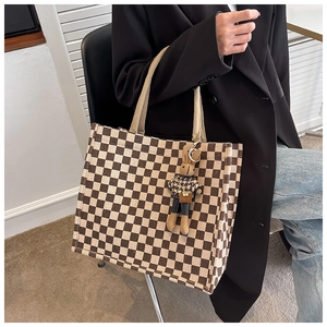 Detail of checkered canvas tote bag with soft plush rabbit charm and woven handle