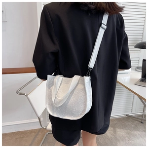 Detail showing the white floral textured canvas bag with adjustable strap and top handle