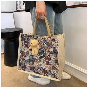 Detailed view of linen tote bag with woven bear patterns and plush bear charm