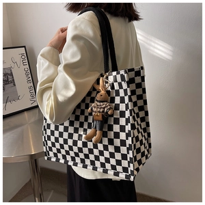 Side view of a large checkerboard canvas tote bag featuring a cute plush bunny pendant
