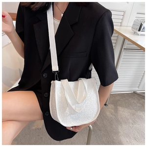 Detail of white embossed small square crossbody bag with wide shoulder strap on model