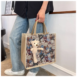 Detail of linen tote bag with woven bear pattern and plush toy bear charm
