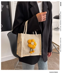 Detailed shot of beige linen lunch bag with 3D yellow knit flower and rope handles