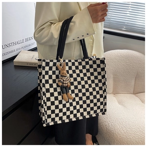 Detail of checkered canvas tote bag with a small plush rabbit charm and wide handles