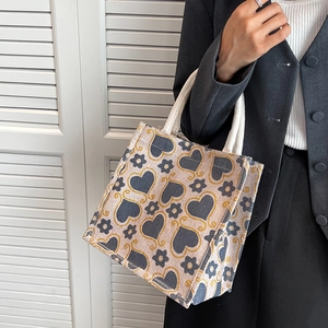 Large floral tote bag with heart patterns and thick cotton rope handles shown on model