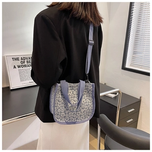 Detail of floral canvas crossbody bag with adjustable strap and small tote handles