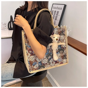 Detail of vintage bear pattern tote bag with rope handle and plush bear charm on a model