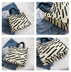 Dettagli della borsa tote in tela beige con strisce artistiche nere e manici in corda
