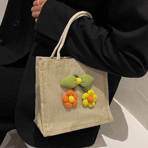 Linen bento bag with hand-knitted flowers and soft rope handles for a minimalist style