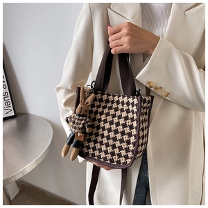 Detail of checkered knit tote bag with brown handles and a cute bunny charm