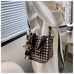Detail of houndstooth canvas tote bag with plush bunny charm and crossbody strap