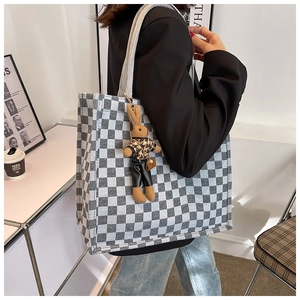 Detail of checkered canvas tote bag with a cute rabbit charm in a modern minimalist setting