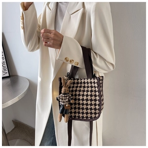 Detail view of plaid canvas handbag with a cute brown rabbit plush charm on a beige blazer