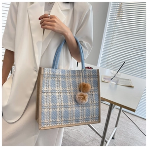 Detail of blue and white tweed tote bag with plush charm and side webbing trim