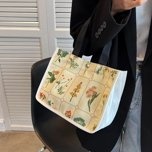 Floral canvas tote bag with black handles and metal snap button shown on shoulder