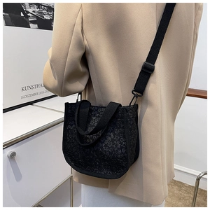 Detail of black floral textured canvas crossbody bag with top handle and shoulder strap
