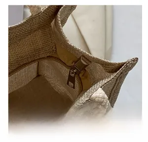 Detail showing smooth metal zipper closure and woven rope handle on the linen tote bag