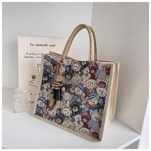 Detail of linen tote bag featuring cartoon bear print and cute plush rabbit charm