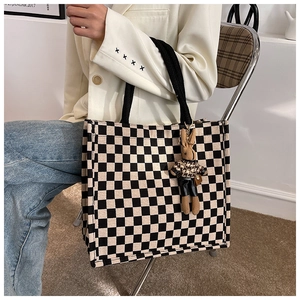 Lifestyle view of checkerboard canvas tote bag with a cute rabbit doll charm