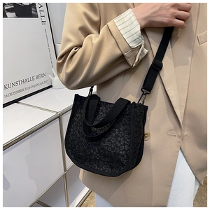Detail of black small square bag with 3D floral texture and adjustable shoulder strap