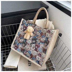 Detail of linen tote bag with cartoon bear patterns and plush bear keychain in a basket