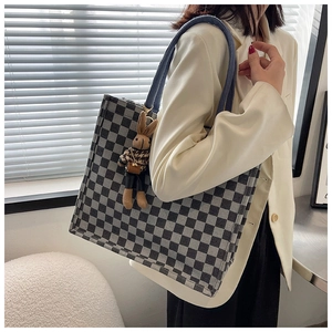 Detail of checkered tote bag with blue straps and cute rabbit plush charm