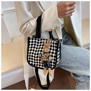 Detail of checkered houndstooth crossbody bag with cute plush rabbit charm and strap