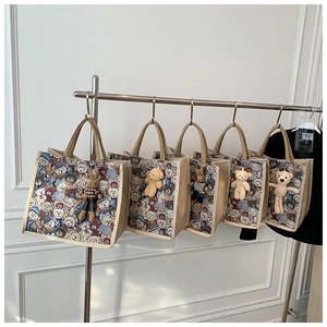 Close-up of five linen tote bags with vintage bear prints and matching plush charms