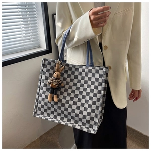Close-up of grey checkerboard canvas tote bag with a cute rabbit doll charm and blue handles