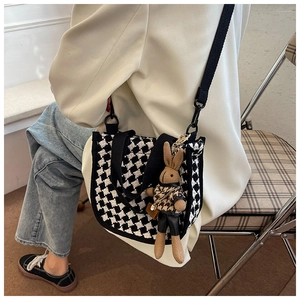 Detail of houndstooth crossbody bag featuring a cute brown plush rabbit pendant charm