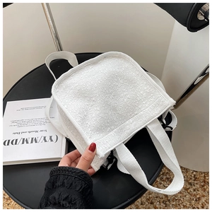 Detail view of white floral jacquard fabric texture and woven strap on a stylish handbag
