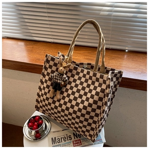 Detail of canvas tote bag showing checkerboard pattern with a rabbit charm and magnetic clasp