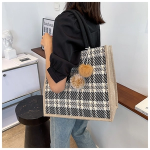Detail of large woven tote bag featuring black and white plaid pattern and rope handles