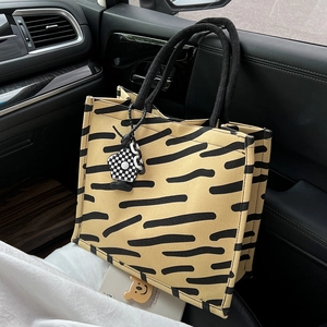 Grande borsa tote gialla con motivo tigrato, manici intrecciati e ciondolo a scacchi