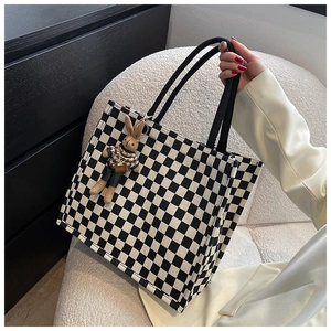 Close-up of checkered canvas tote bag with a cute plush rabbit charm on handle