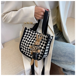 Detail of mini houndstooth tote bag featuring a cute bunny charm on white blazer outfit