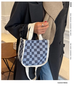 Détail d'un sac cabas en toile à damier bleu et blanc avec des poignées tissées