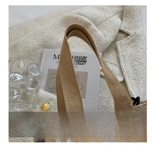 Détail des poignées tissées et du crochet en métal noir sur le sac à main en toile