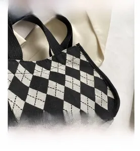 Detail einer kleinen Canvas-Tasche mit schwarz-weißem Argyle-Muster und gewebtem Tragegurt