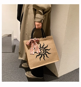 Détail du sac cabas en jute avec imprimé soleil et foulard en soie fleuri sur l'anse