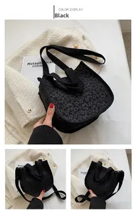 Detail of black floral canvas handbag showing intricate jacquard fabric and strap textures
