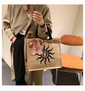 Détail d'un sac cabas en lin avec imprimé soleil et foulard floral rouge sur l'anse
