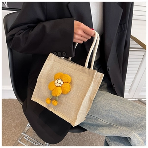 Close-up of beige linen lunch bag featuring a 3D yellow fabric flower and woven handles